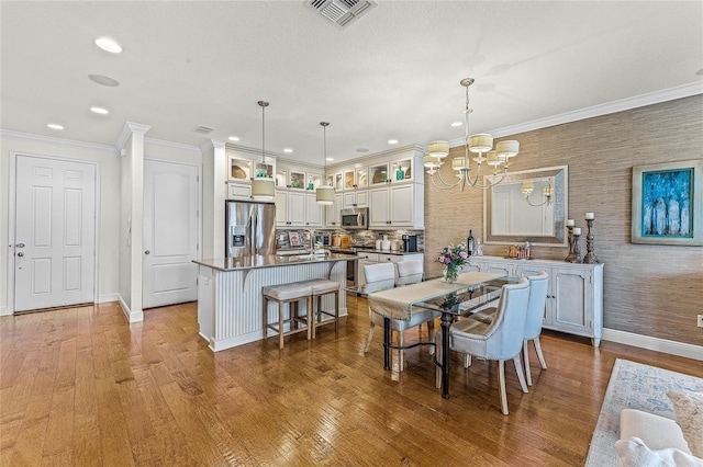 dining area with an inviting chandelier, ornamental molding, and wood-type flooring