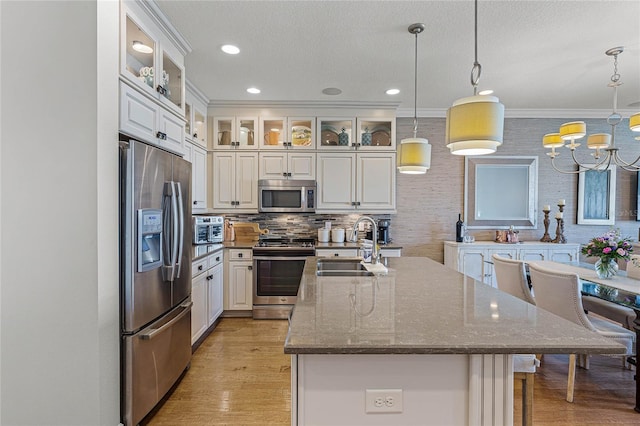 kitchen featuring stainless steel appliances, hanging light fixtures, sink, and white cabinets