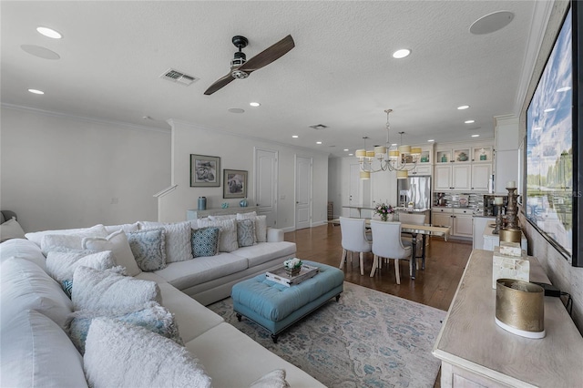 living room featuring crown molding, dark wood-type flooring, ceiling fan with notable chandelier, and a textured ceiling