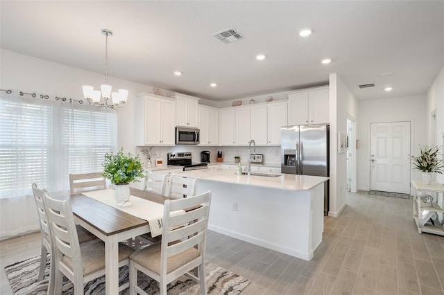 kitchen featuring white cabinetry, hanging light fixtures, stainless steel appliances, and sink