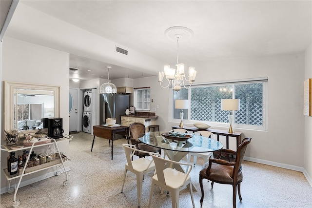 dining area with an inviting chandelier and stacked washer and clothes dryer