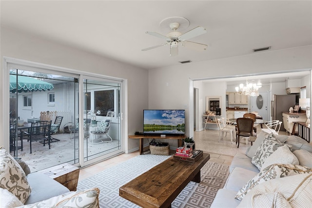 tiled living room featuring ceiling fan with notable chandelier