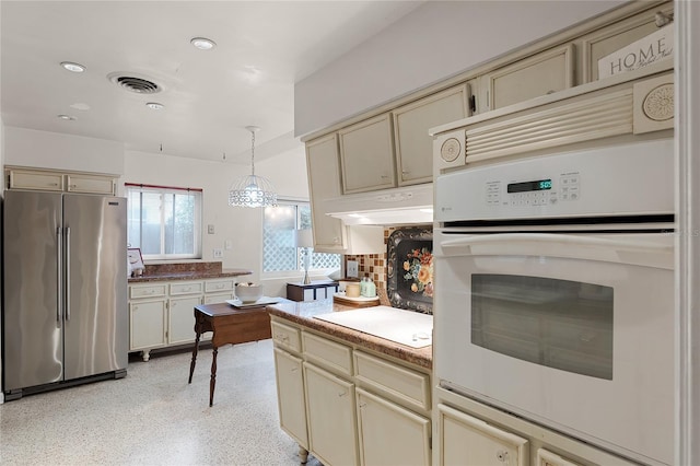 kitchen featuring pendant lighting, high end refrigerator, white cooktop, and cream cabinets