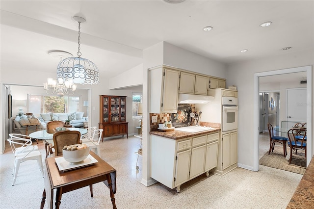 kitchen featuring pendant lighting, decorative backsplash, white appliances, and cream cabinetry