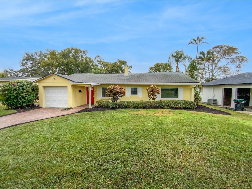 ranch-style home featuring cooling unit, a garage, and a front lawn