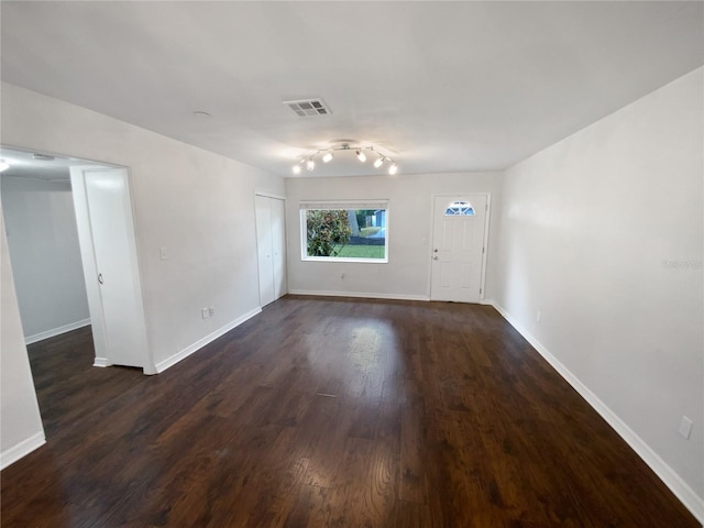 spare room featuring track lighting and dark hardwood / wood-style floors