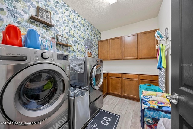 laundry area with separate washer and dryer, cabinets, a textured ceiling, and light wood-type flooring