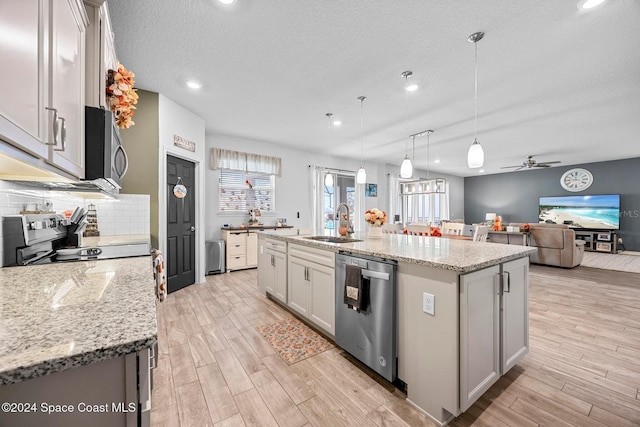 kitchen featuring pendant lighting, tasteful backsplash, an island with sink, sink, and stainless steel appliances