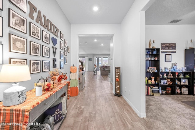 hallway with a textured ceiling and light wood-type flooring