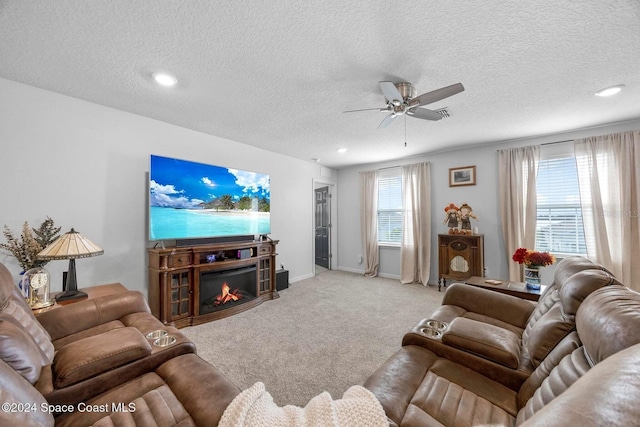 living room with ceiling fan, light carpet, and a textured ceiling