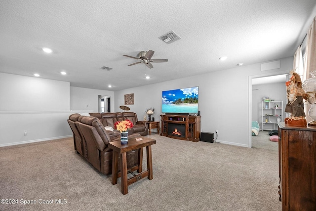 living room featuring ceiling fan, light colored carpet, and a textured ceiling