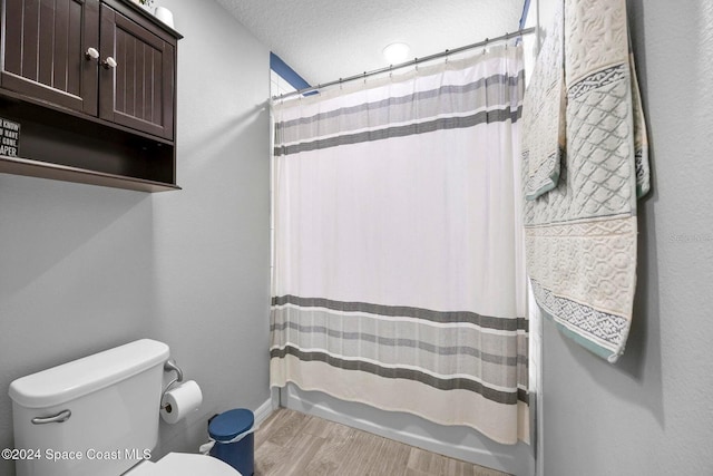 bathroom with wood-type flooring, shower / bath combination with curtain, a textured ceiling, and toilet