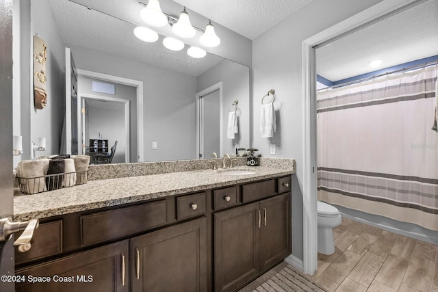 full bathroom featuring shower / bath combination with curtain, vanity, toilet, and a textured ceiling