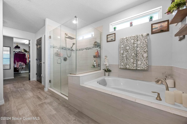 bathroom featuring separate shower and tub and a textured ceiling