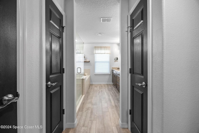 bathroom with vanity, hardwood / wood-style floors, a textured ceiling, and a tub to relax in