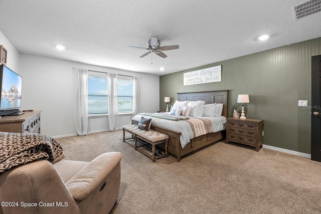 bedroom featuring ceiling fan, light carpet, and a textured ceiling