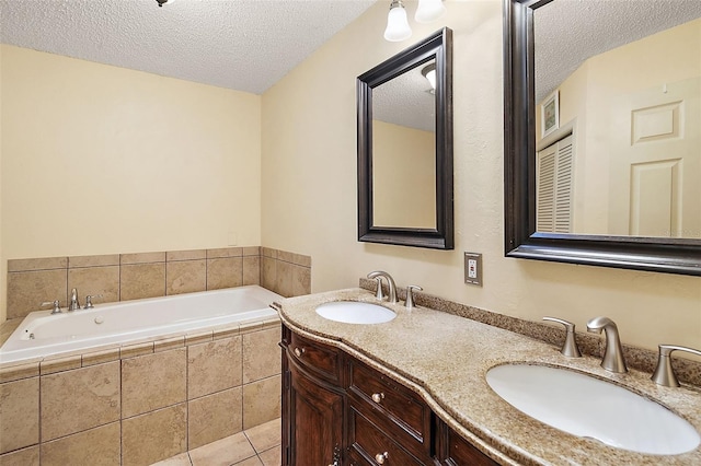 bathroom featuring tile patterned flooring, vanity, tiled bath, and a textured ceiling