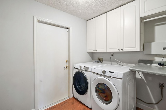 laundry room with cabinets, a textured ceiling, light hardwood / wood-style flooring, and washing machine and clothes dryer