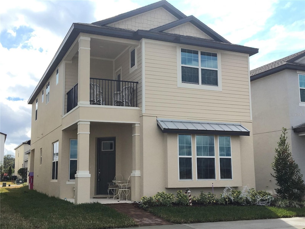 view of front facade with a balcony and a front lawn