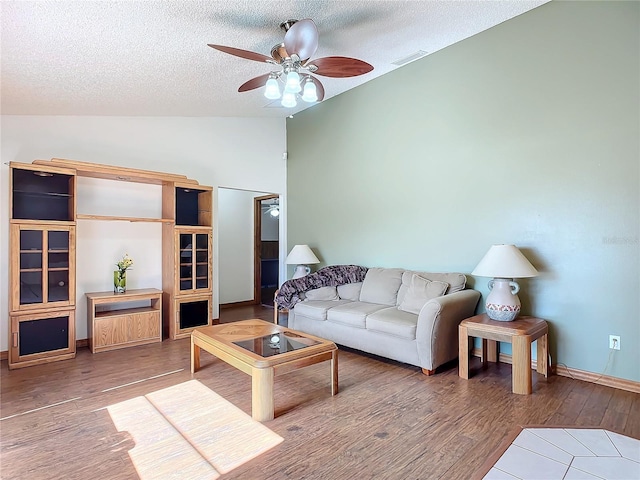 living room with ceiling fan, lofted ceiling, hardwood / wood-style floors, and a textured ceiling