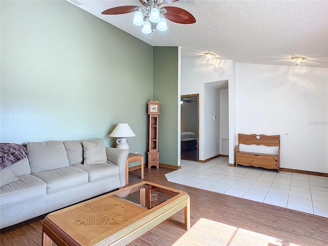 living room with ceiling fan, lofted ceiling, a textured ceiling, and light tile patterned floors