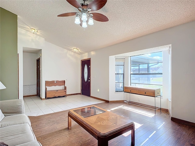 unfurnished living room with ceiling fan, vaulted ceiling, a textured ceiling, and light wood-type flooring