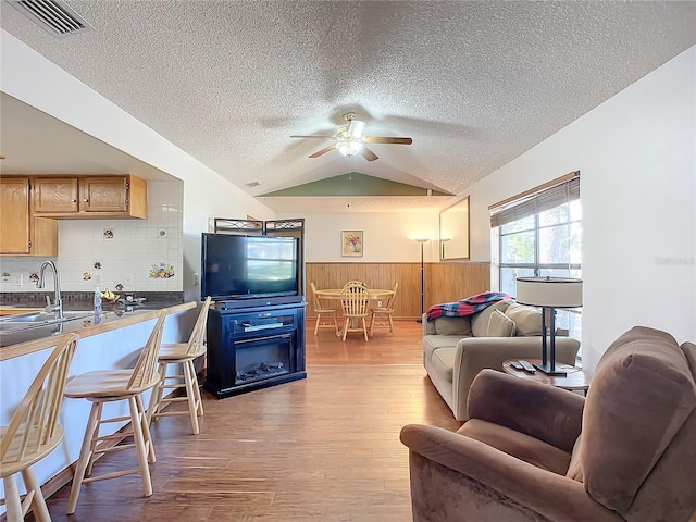 living room with vaulted ceiling, sink, a textured ceiling, and ceiling fan