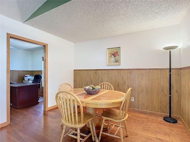 dining space with wood-type flooring and a textured ceiling