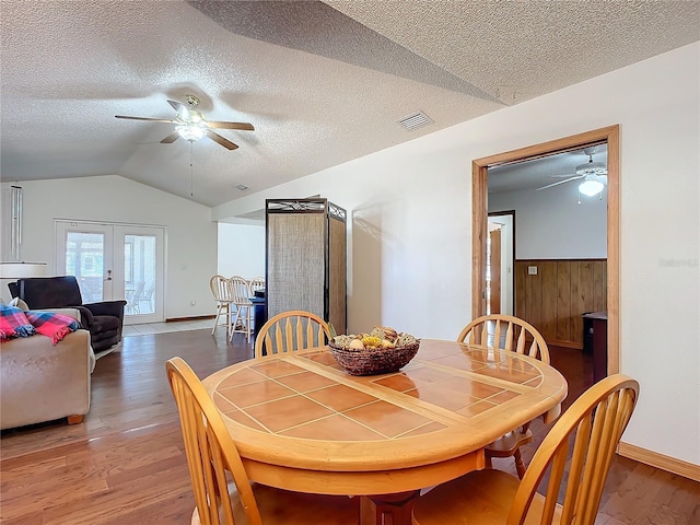 dining area with french doors, ceiling fan, wood-type flooring, and vaulted ceiling