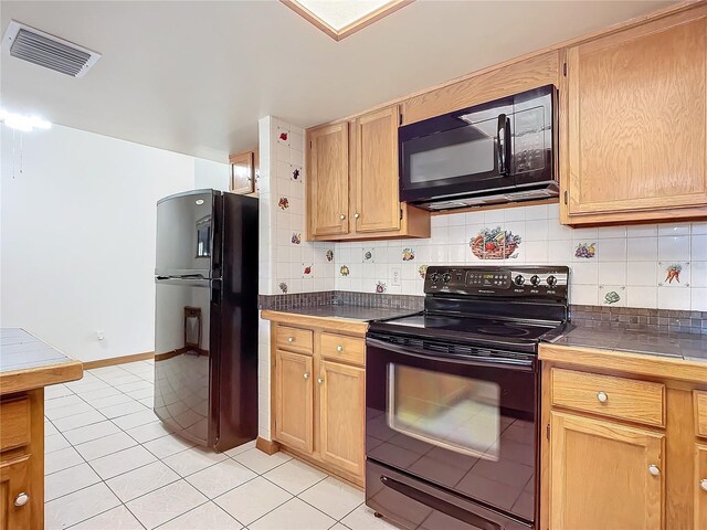 kitchen with light tile patterned floors, backsplash, tile countertops, and black appliances