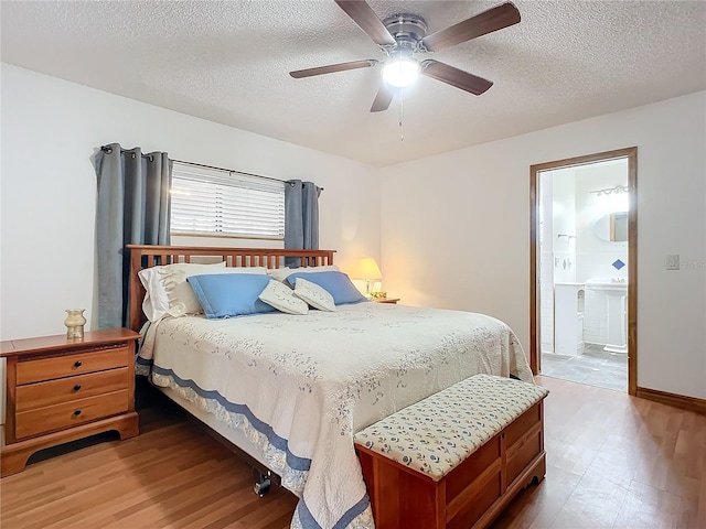 bedroom featuring hardwood / wood-style flooring, ceiling fan, connected bathroom, and a textured ceiling