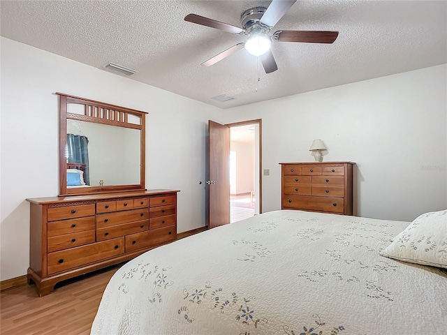 bedroom with hardwood / wood-style flooring, ceiling fan, and a textured ceiling