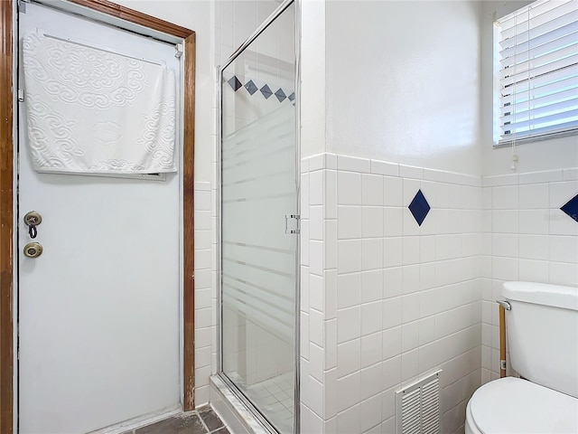 bathroom featuring toilet and a shower with shower door