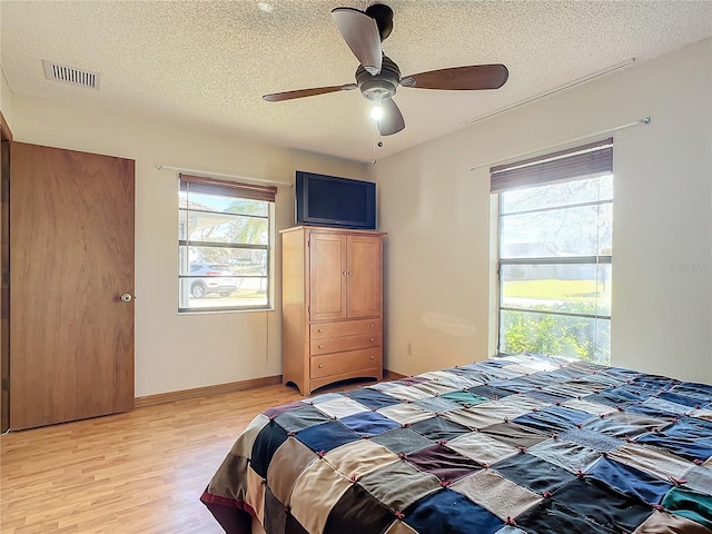 bedroom featuring multiple windows, a textured ceiling, ceiling fan, and light hardwood / wood-style floors