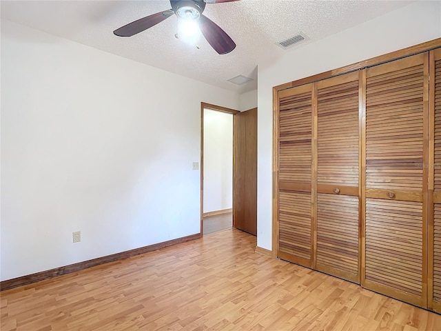 unfurnished bedroom featuring ceiling fan, a textured ceiling, a closet, and light hardwood / wood-style flooring