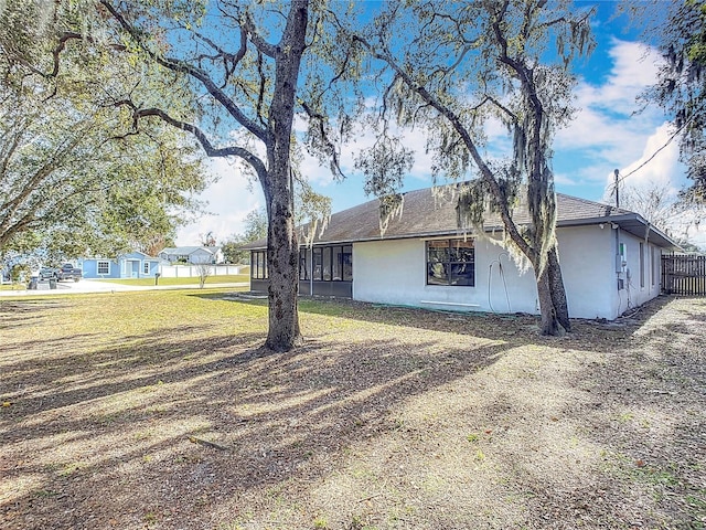 view of side of property with a sunroom and a lawn