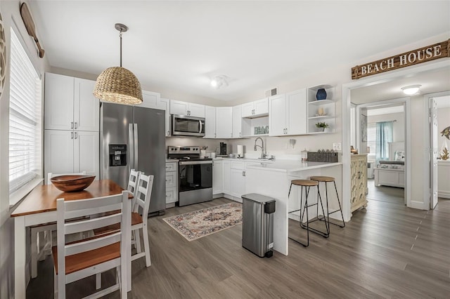 kitchen featuring white cabinetry, hanging light fixtures, stainless steel appliances, and kitchen peninsula