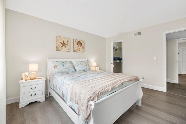 bedroom with a spacious closet, wood-type flooring, and a closet