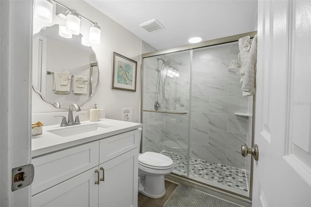 bathroom featuring vanity, wood-type flooring, a shower with door, and toilet