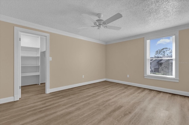 unfurnished bedroom featuring crown molding, a walk in closet, and light hardwood / wood-style floors