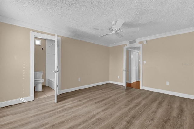 unfurnished bedroom featuring ornamental molding, a textured ceiling, light hardwood / wood-style floors, and ensuite bath