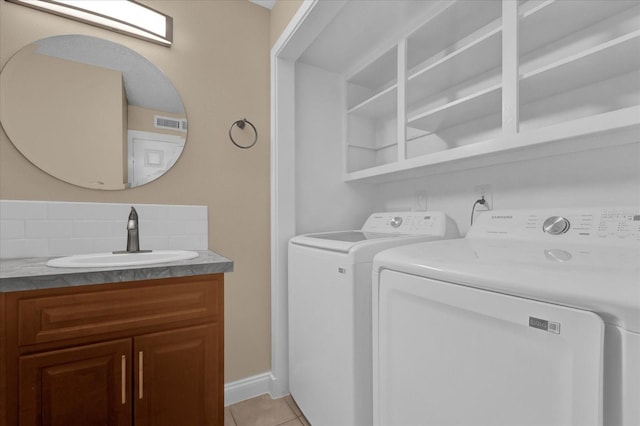 clothes washing area featuring sink, light tile patterned floors, and washer and clothes dryer