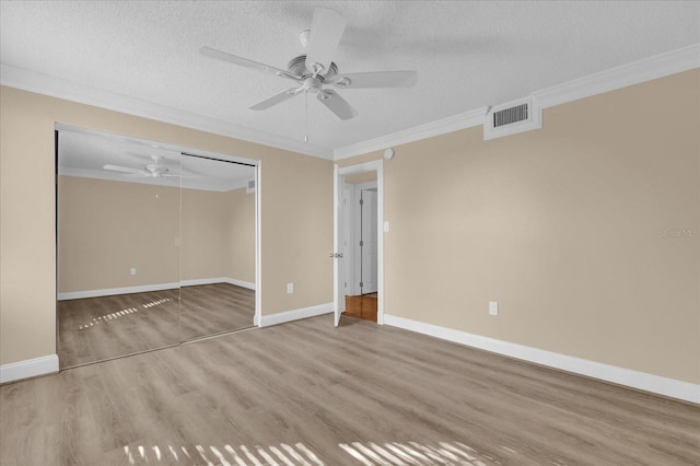 empty room with crown molding, ceiling fan, wood-type flooring, and a textured ceiling