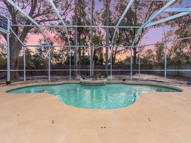 pool at dusk featuring a lanai and a patio area