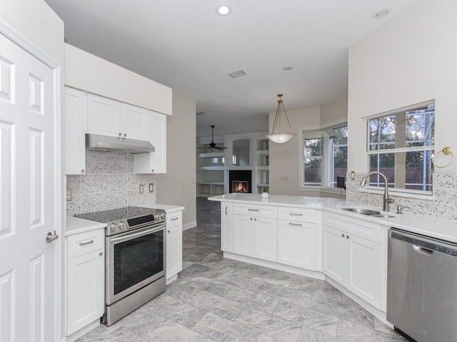 kitchen featuring appliances with stainless steel finishes, pendant lighting, white cabinetry, sink, and kitchen peninsula