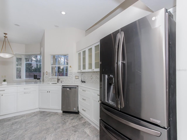 kitchen with sink, white cabinetry, backsplash, stainless steel appliances, and decorative light fixtures