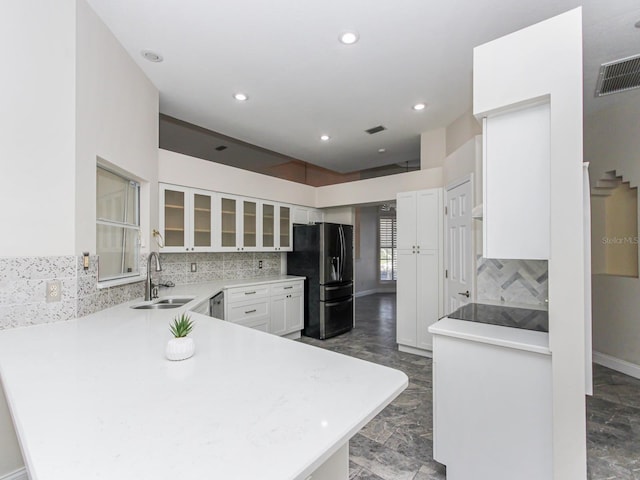 kitchen with sink, fridge with ice dispenser, tasteful backsplash, white cabinets, and kitchen peninsula