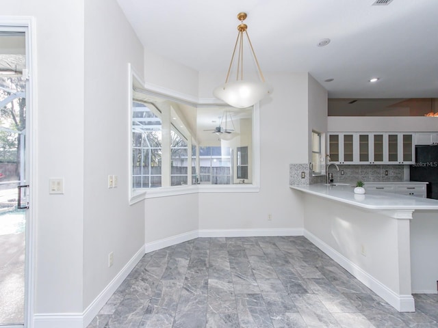 kitchen with a breakfast bar, pendant lighting, sink, decorative backsplash, and kitchen peninsula