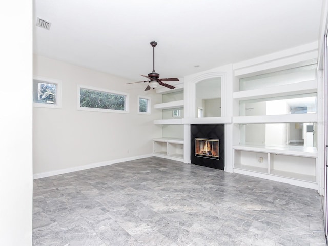 unfurnished living room featuring ceiling fan and built in shelves