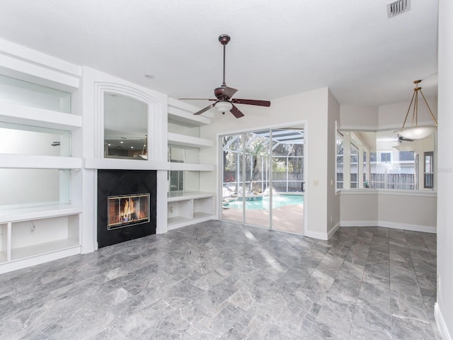 unfurnished living room featuring built in shelves and ceiling fan